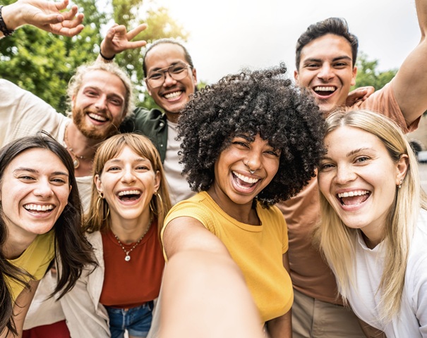 Multicultural friends smiling at camera together outside - Happy young people taking selfie with smart mobile phone device walking on city street - Youth community and technology concept