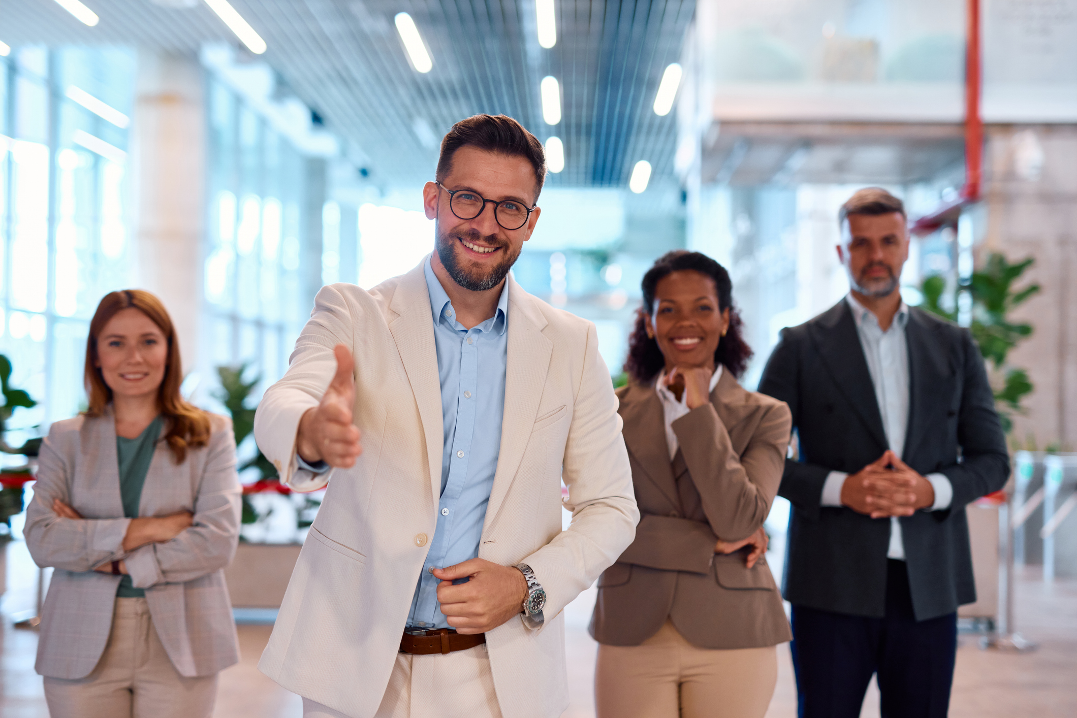Businessman offering handshake with his team in the background